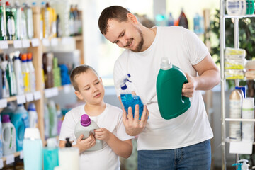 Obraz premium Young man with his son buyers choosing detergent in household chemicals store