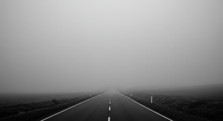 Vast empty road disappearing into thick fog, creating a dramatic and mysterious atmosphere