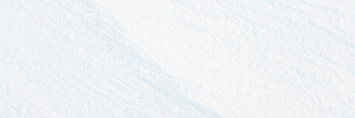 Wide panoramic winter background with snowy ground. Natural snow texture. Wind sculpted patterns on snow surface.