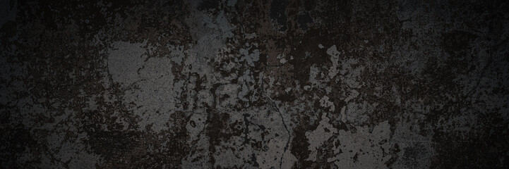 Dark wide panoramic background. Peeling paint on a concrete wall. Dark grunge texture of old cracked flaking paint. Weathered rough painted surface. Patterns of cracks. Darkness background for design.