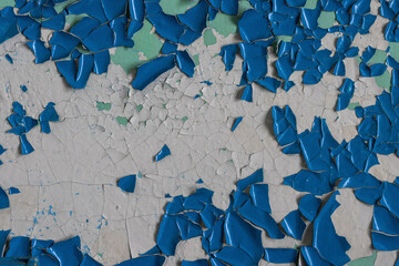 Blue peeling paint on the wall. Old concrete wall with cracked flaking paint. Weathered rough painted surface with patterns of cracks and peeling. High resolution texture for background and design.