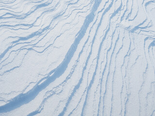 Beautiful winter background with snowy ground. Natural snow texture. Wind sculpted patterns on snow surface. Arctic, Polar region.