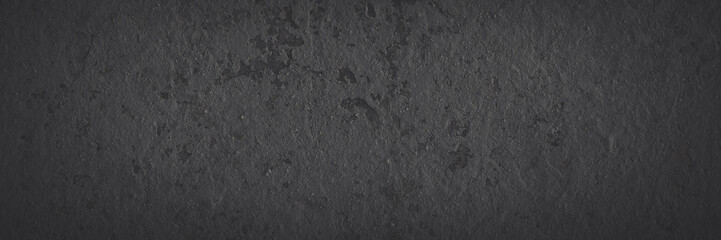 Dark wide panoramic background. Peeling paint on a concrete wall. Faded dark texture of old cracked flaking paint. Weathered rough painted surface with patterns of cracks. Shaded background for design