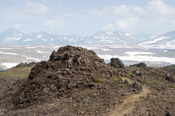 Summer mountain landscape. Hiking trail among the rocks and petrified lava on the slope of the volcano. Travel and hiking on the Kamchatka Peninsula. Nature of the Russian Far East. Kamchatka, Russia.