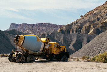 Old mixer truck parked on deserted ground showcasing rugged landscape forms.