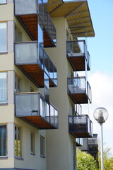 Modern apartment building with glass balconies and clear blue sky in a suburban area