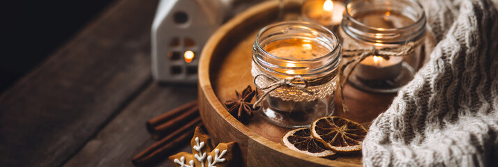 Banner. Creative handmade christmas home decor decorations: simple glass jars with aroma candles decorated with a ribbon, cinnamon, anise, dry orange. Cozy atmospheric composition for holiday mood
