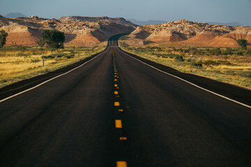 A winding road stretches through vibrant landscapes and rocky terrain under blue sky.