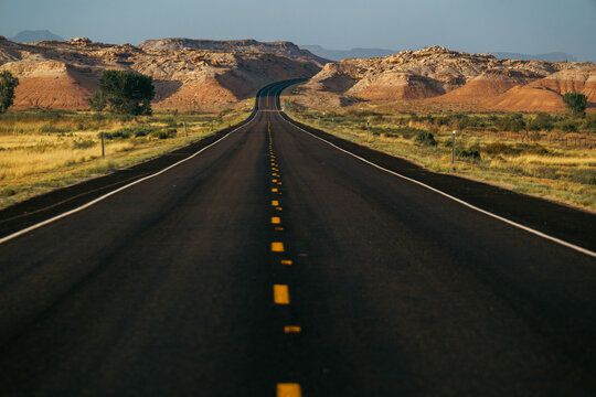 A winding road stretches through vibrant landscapes and rocky terrain under blue sky.