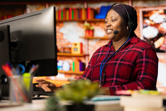 Smiling call center agent talking in headset microphone, helping customers regain access to accounts and devices. Happy woman in customer center assisting clients needing help resetting password