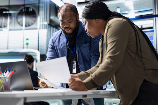Group of professional consultants reviewing data and checklists in a high tech solar panel plant, ensuring manufacturing process meets sustainable energy and innovation standards.
