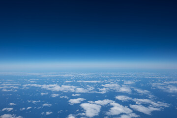 Aerial view of scattered white clouds above deep blue ocean. Atmospheric gradient from light to...