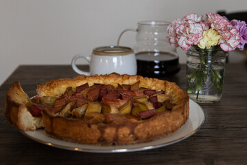 freshly baked Rhubarb pie on a dark wooden table. piece of a hommade bakery with coffee in a morning` lightning