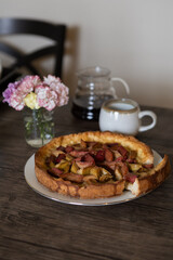 freshly baked Rhubarb pie on a dark wooden table. piece of a hommade bakery with coffee in a morning` lightning