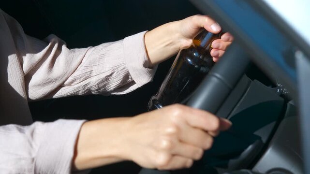Woman drinking beer while driving car. Female driver opening beer bottle while operating vehicle, demonstrating reckless alcohol-related behavior and potential legal consequences of impaired driving