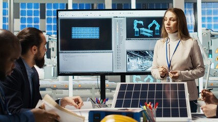 Investors meeting with photovoltaics factory manager to review solar cell designs in office. Solar...