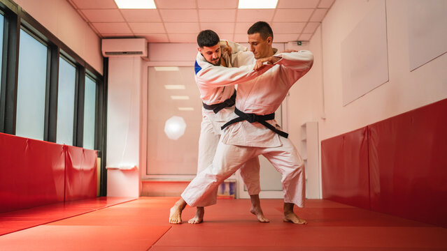 Two men grappling during judo training session in dojo
