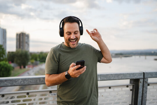 Happy man enjoying music on a bridge in the city - Powered by Adobe
