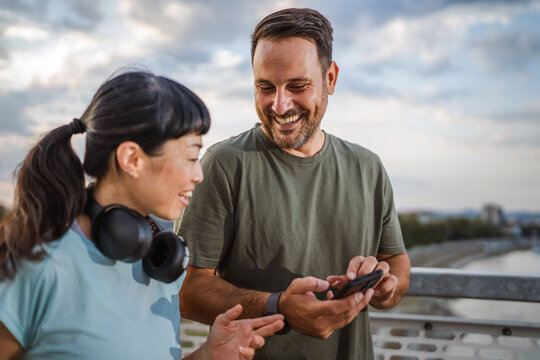 Couple sharing fitness progress on smart phone after workout
