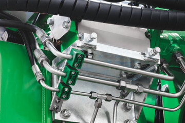 Close up of a machine with a green hose. The hose is attached to a machine with a green cover