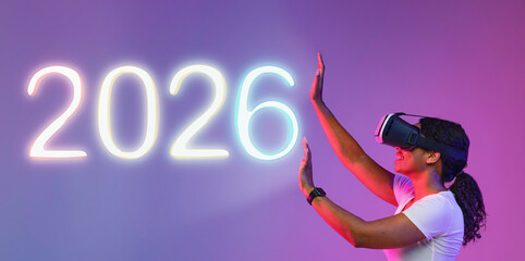 Young Black female in VR glasses touches an imaginary wall while immersed in a virtual reality...