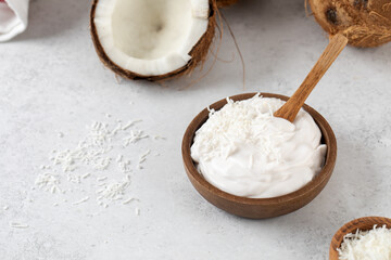 Fresh coconut yogurt in a wooden bowl with a wooden spoon and coconuts. Plant yogurt, lactose-free.