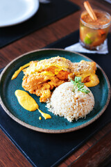 portion of fish as a main course and with yellow sauce on top, accompanied by rice and cocktail decoration.