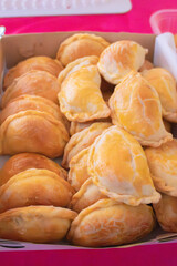 Empanadas horneadas doradas en caja de cartón, fotografía gastronómica que resalta tradición y sabor casero.