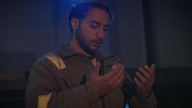 A Muslim man in work clothes raising his hands in prayer and making dua at the workplace. The video reflects faith, spirituality, and devotion in daily life.