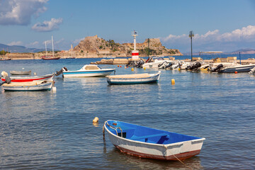 Fototapeta premium Small boats moored in marina with view of Old Fortress in Corfu Greece in sunny day