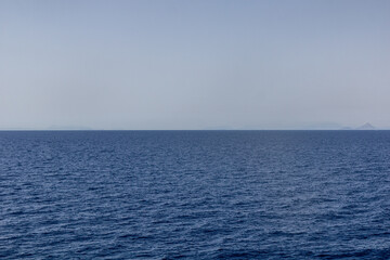 Flat blue sea with islands in a distance, Greece