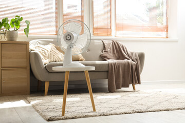 Fototapeta premium Electric fan on table in living room interior