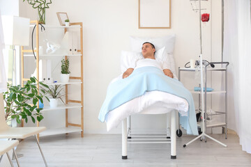 Male patient transfusing blood on bed in hospital ward