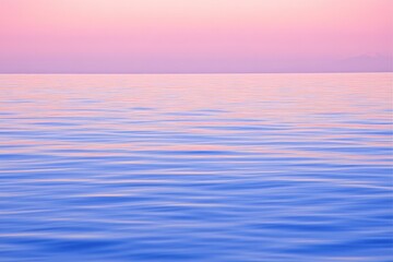 Obraz premium Calm ocean surface at sunrise, soft pink hues