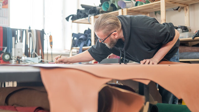 Caucasian bearded man working as a tanner in a workshop.  - Powered by Adobe