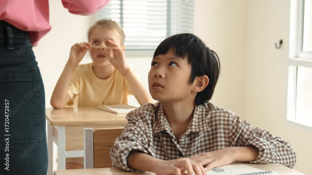 Poster asian elementary student looking at teacher while attend in classroom. diverse smart student sitting