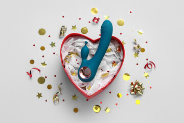 Composition with gift box, vibrator and confetti on grey background
