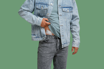 Naklejka premium Young man with medical patch after appendix surgery on green background, closeup