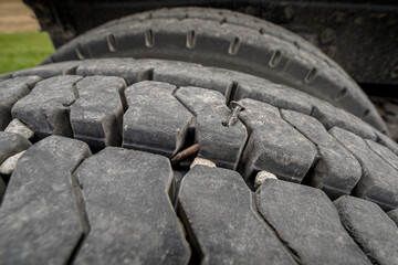 Nail stuck in tire tread on heavy duty grain truck tires. Tire inspection, flat tire, maintenance and safety concept.