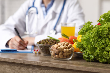Young female nutritionist with clipboard and healthy food writing diet plan in office, closeup