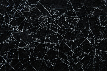 Broken glass texture with intricate crack patterns on a black background. The detailed shards and...