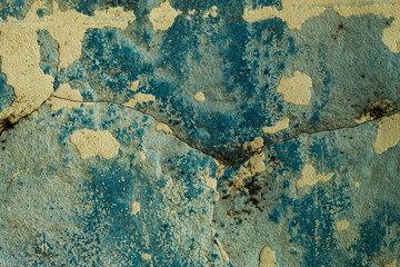 wall texture with peeling and cracked blue paint, revealing a layer of gray cement plaster