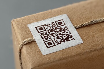 Detailed close-up of a Kraft gift box adorned with a textured label showcasing a black and white QR code symbolizing the merger of traditional packaging with modern digital interaction