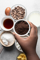 Cocoa powder in a white ceramic bowl, clumpy cocoa powder into a small white bowl