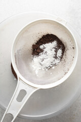 Sifting cocoa powder for baking, a plastic sieve with cocoa powder in it