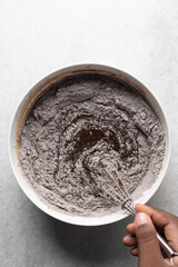 Overhead view of flour and cocoa powder being whisked into chocolate batter, process of making chocolate mud cake, making a dark chocolate cake