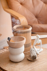 Bowl with Palo Santo, incense and statuette on board in room, closeup