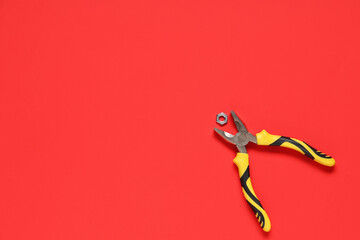 Pliers with chrome nut on red background