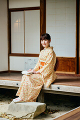 縁側で静かに佇む着物姿の女性