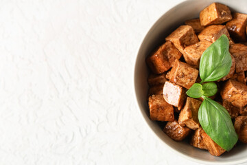 Bowl with pieces of fried tofu cheese and basil on white background